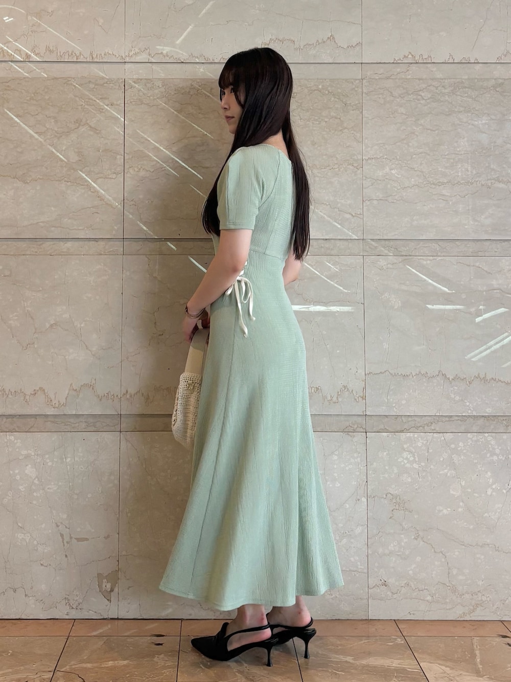 グリーン系のワンピース、ブラック系のパンプス、ホワイト系のショルダーバッグを着用したレディースの夏コーディネートの3枚目の写真