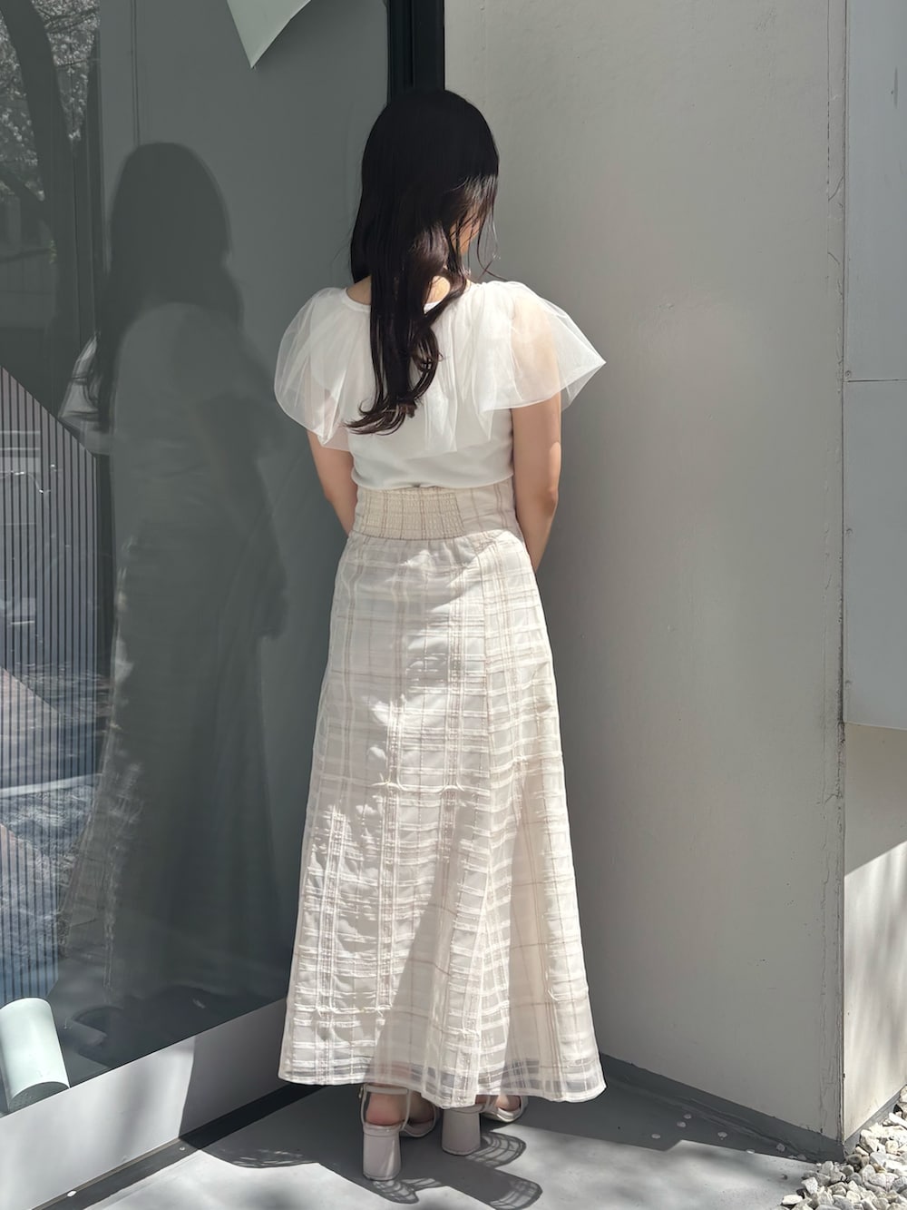 ホワイト系のスカート、ベージュ系のサンダル、ホワイト系のニット/セーターを着用したレディースの春コーディネートの4枚目の写真