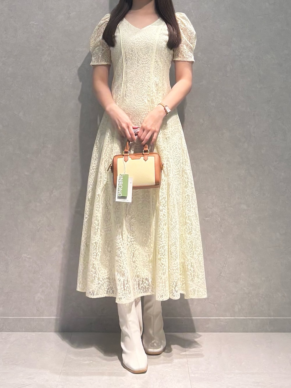 ホワイト系のブーツ、ブラウン系のハンドバッグ、イエロー系のワンピースを着用したレディースの春コーディネートの2枚目の写真