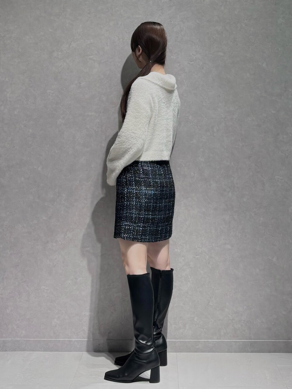 ブラック系のスカート、ブラック系のブーツ、ホワイト系のニット/セーターを着用したレディースの秋コーディネートの3枚目の写真