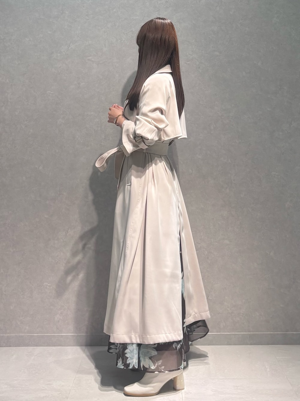 ブラウン系のスカート、ホワイト系のニット/セーター、ホワイト系のトレンチコートを着用したレディースの春コーディネートの3枚目の写真