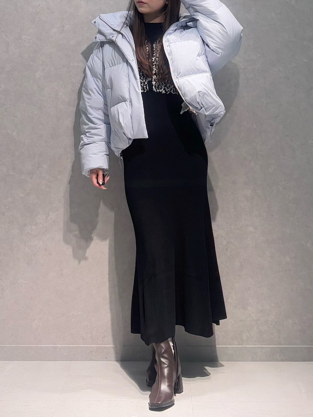 ブラック系のワンピース、ブルー系のダウンジャケット/コート、ブラウン系のブーツを着用したレディースの冬コーディネートの2枚目の写真