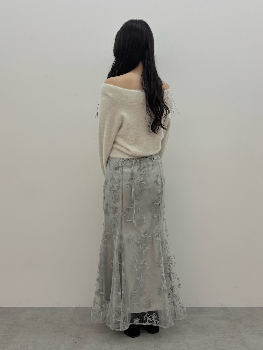 ホワイト系のニット/セーター、ブラウン系のブーツ、グリーン系のスカートを着用したレディースの秋コーディネートの4枚目の写真