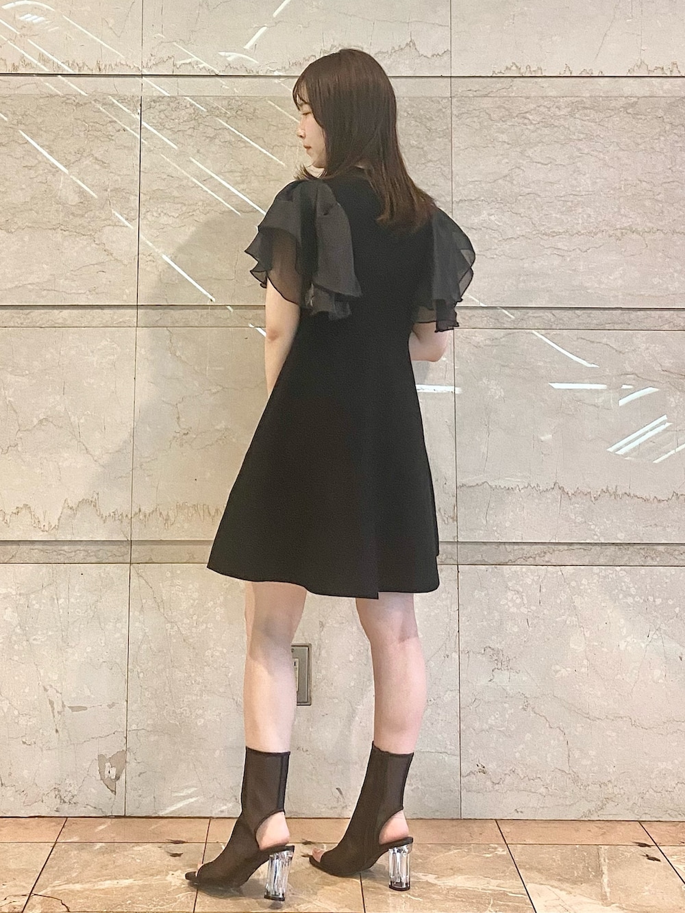 ブラック系のワンピース、ブラック系のブーツを着用したレディースの春コーディネートの3枚目の写真