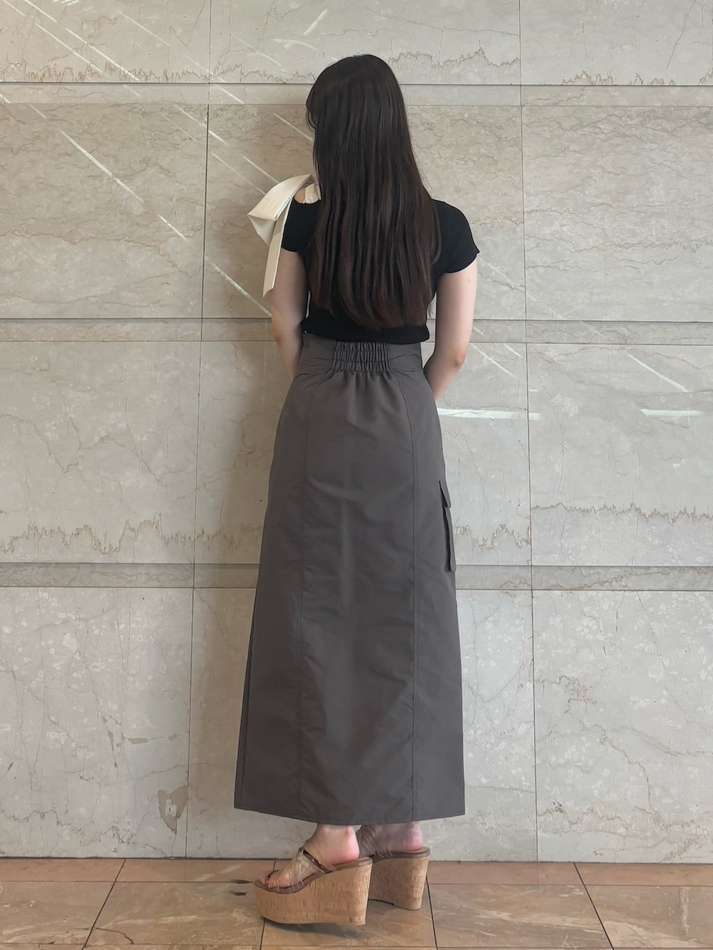 ブラウン系のスカート、ブラウン系のサンダル、ブラック系のニット/セーターを着用したレディースの夏コーディネートの4枚目の写真