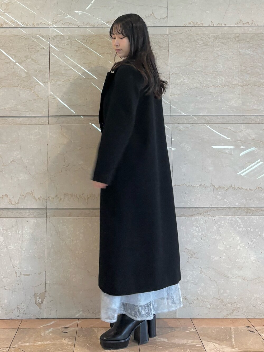 ブルー系のスカート、ブラック系のブーツ、ホワイト系のニット/セーターを着用したレディースの冬コーディネートの3枚目の写真