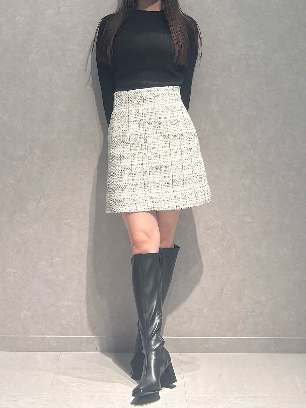 ホワイト系のスカート、ブラウン系のニット/セーター、ブラック系のブーツを着用したレディースの秋コーディネートの2枚目の写真