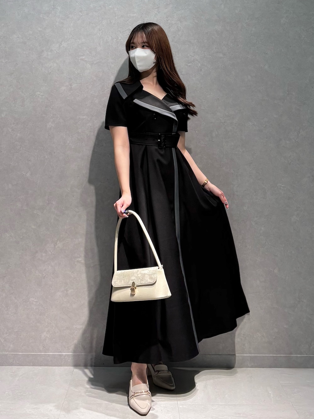 ブラック系のワンピース、ホワイト系のパンプス、ホワイト系のハンドバッグを着用したレディースの春コーディネートの3枚目の写真