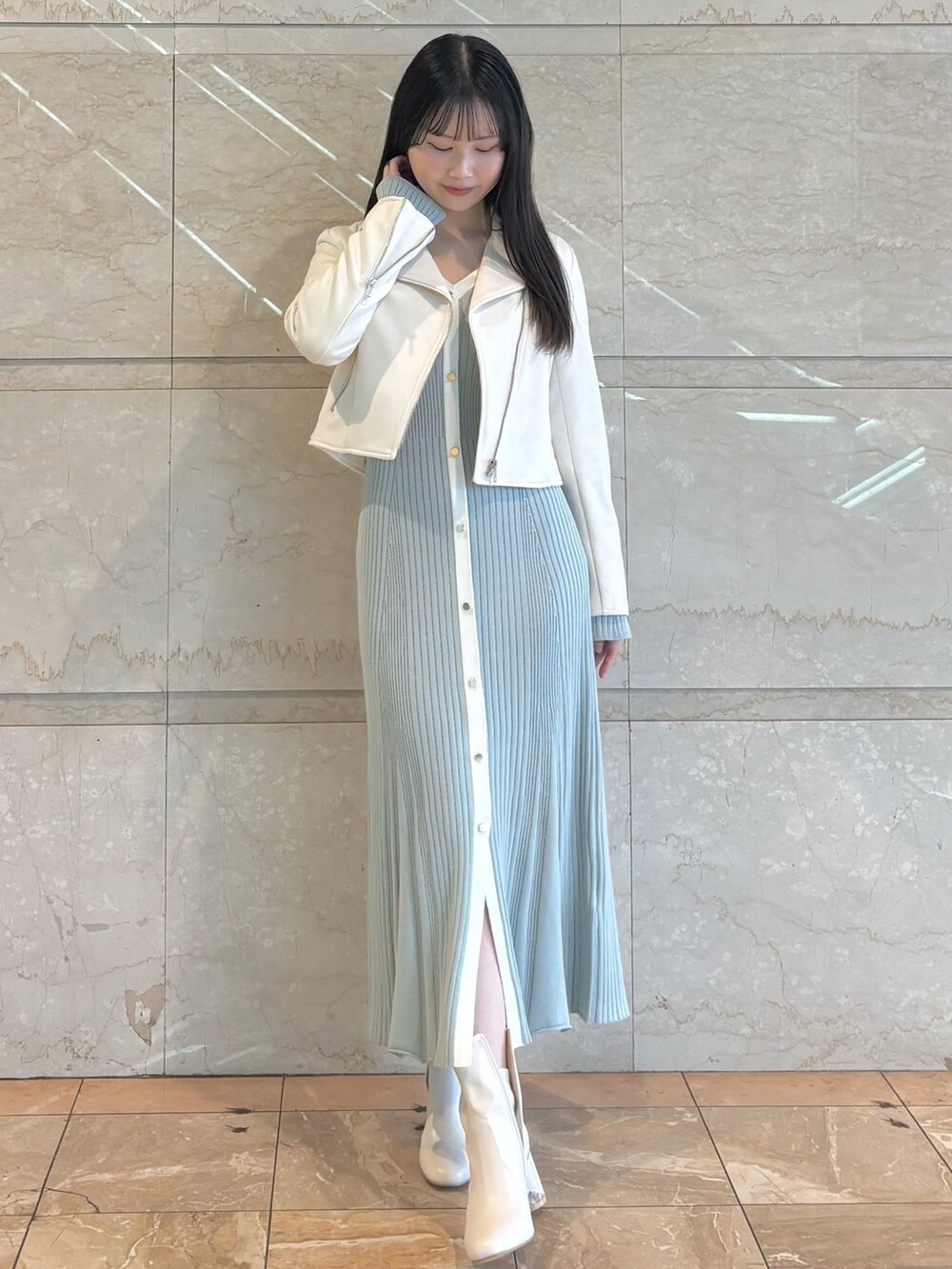 ブルー系のワンピース、ホワイト系のブーツ、ホワイト系のライダースジャケットを着用したレディースの冬コーディネートの2枚目の写真