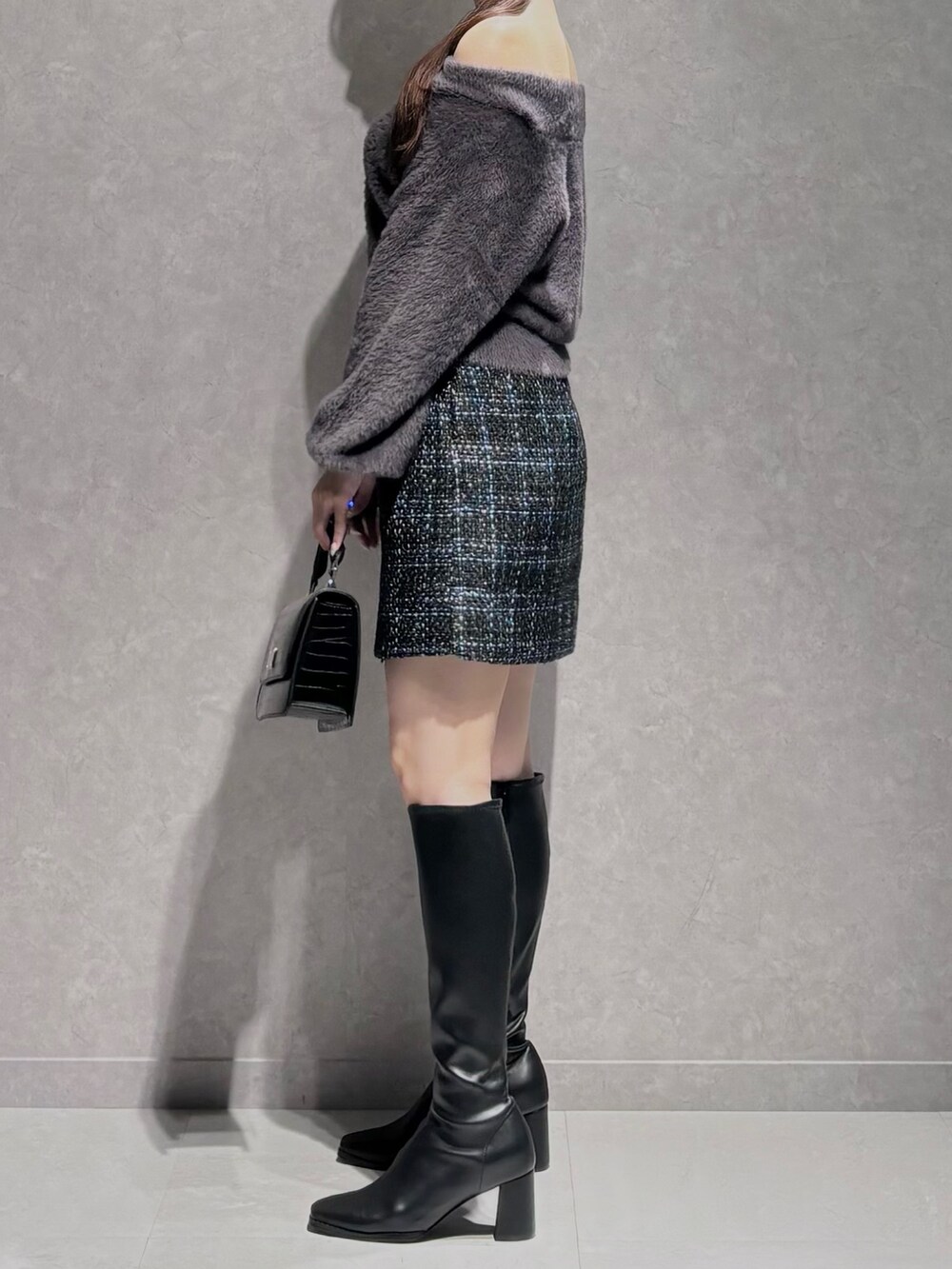 ブラック系のスカート、グレー系のニット/セーター、ブラック系のハンドバッグを着用したレディースの秋コーディネートの4枚目の写真