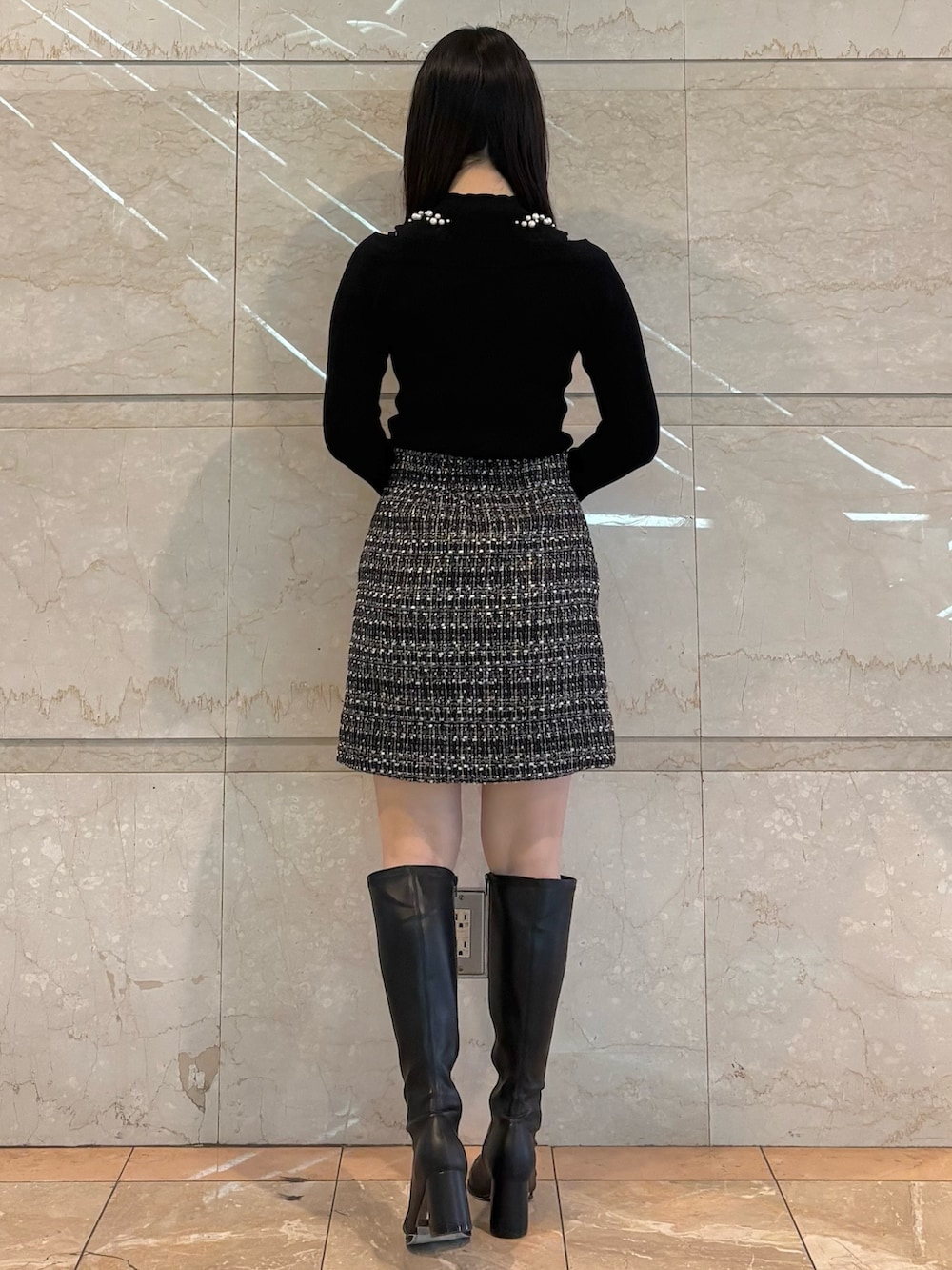 ブラック系のスカート、ブラック系のニット/セーター、ブラウン系のブーツを着用したレディースの冬コーディネートの3枚目の写真