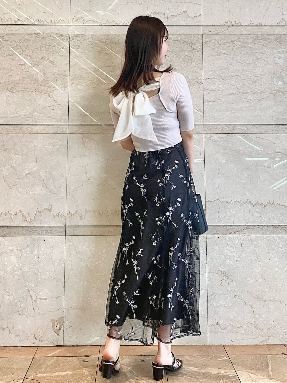 ブラック系のハンドバッグ、グレー系のスカート、ブラック系のサンダルを着用したレディースの春コーディネートの4枚目の写真