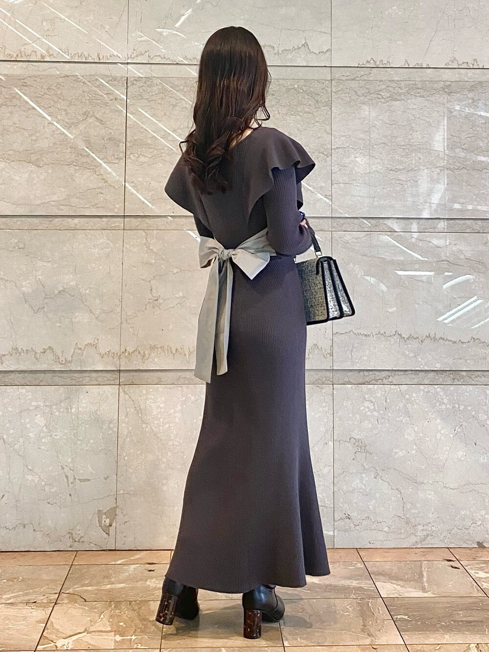 グレー系のワンピース、ブラック系のブーツ、ブラック系のハンドバッグを着用したレディースの冬コーディネートの3枚目の写真