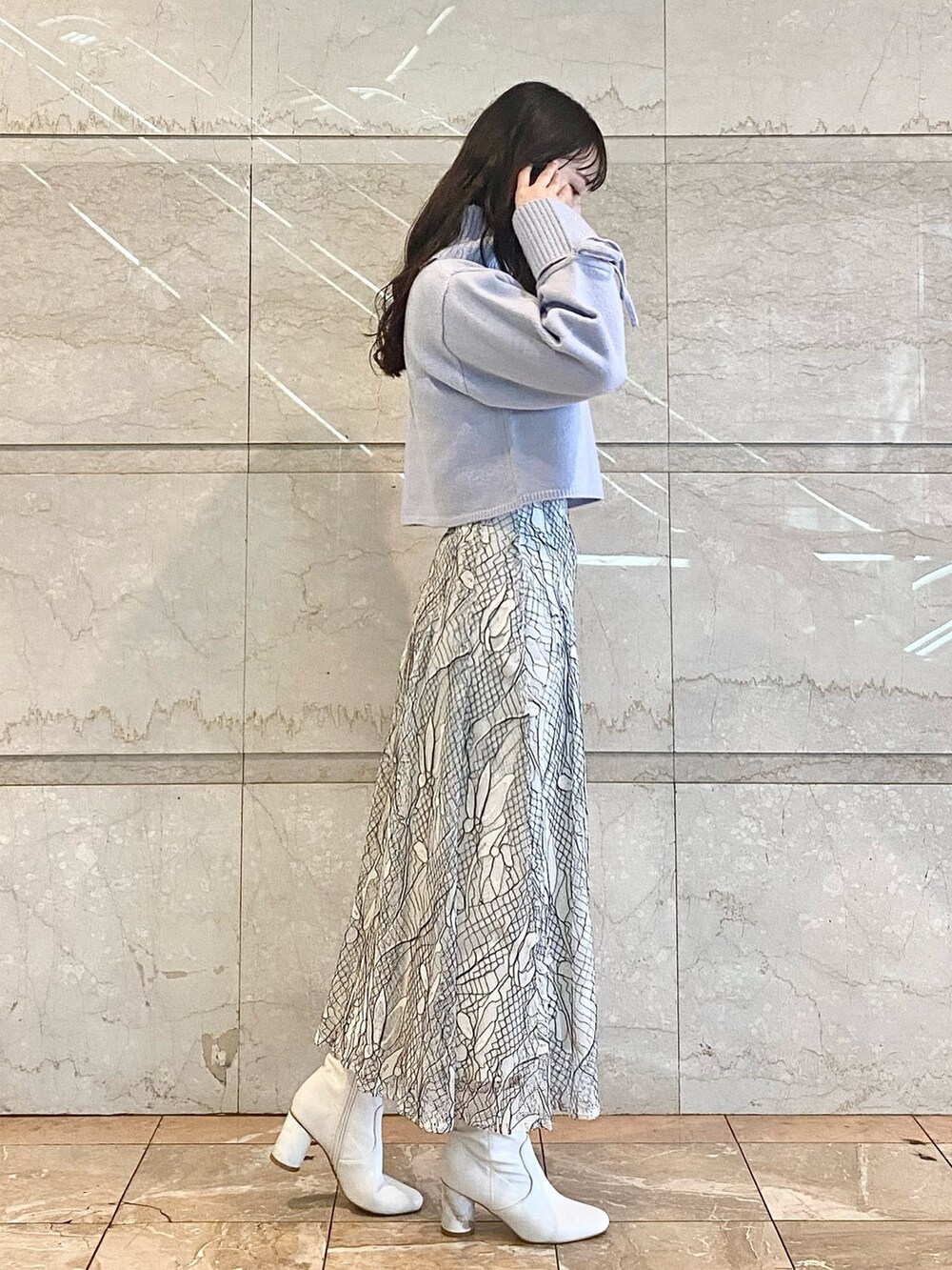 ホワイト系のスカート、ブルー系のニット/セーター、ホワイト系のブーツを着用したレディースの冬コーディネートの4枚目の写真