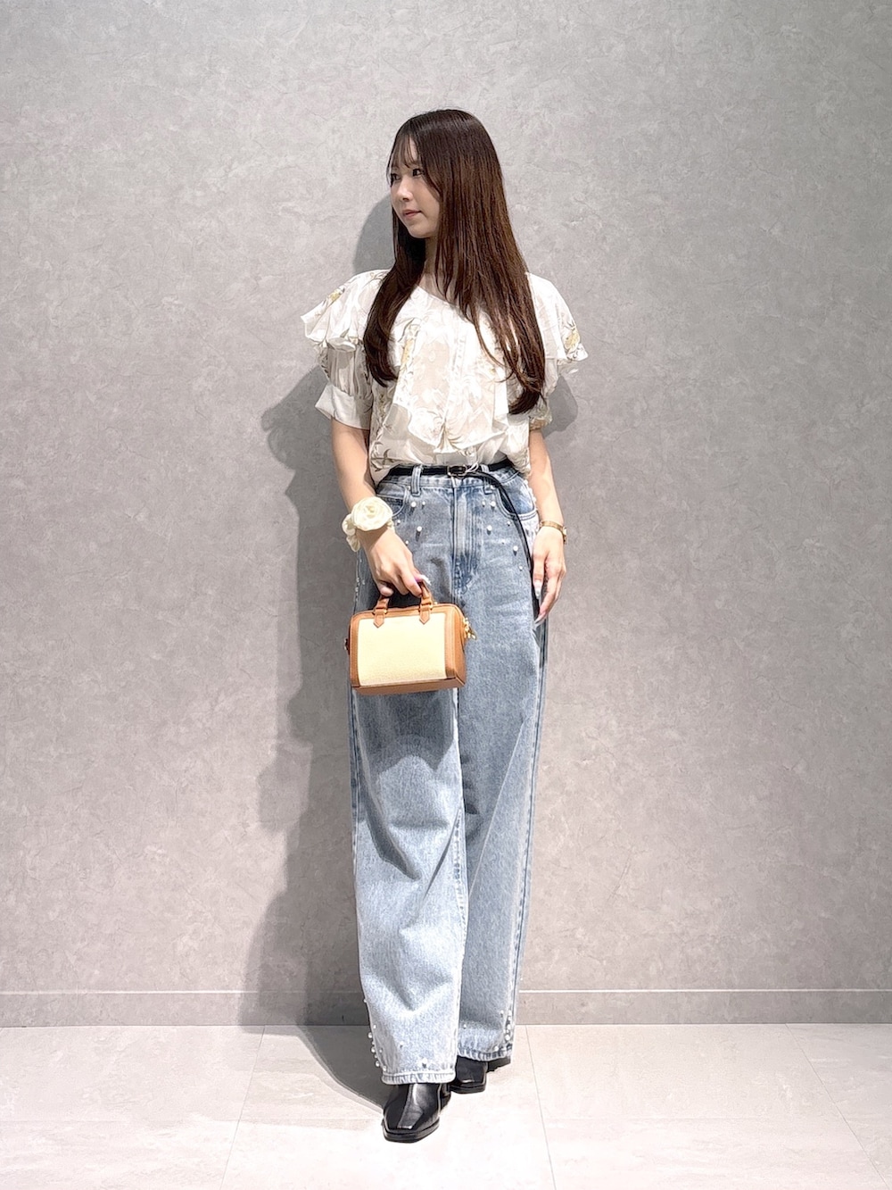 ホワイト系のシャツ/ブラウス、ブラウン系のハンドバッグ、ブルー系のデニムパンツを着用したレディースの秋コーディネートの2枚目の写真