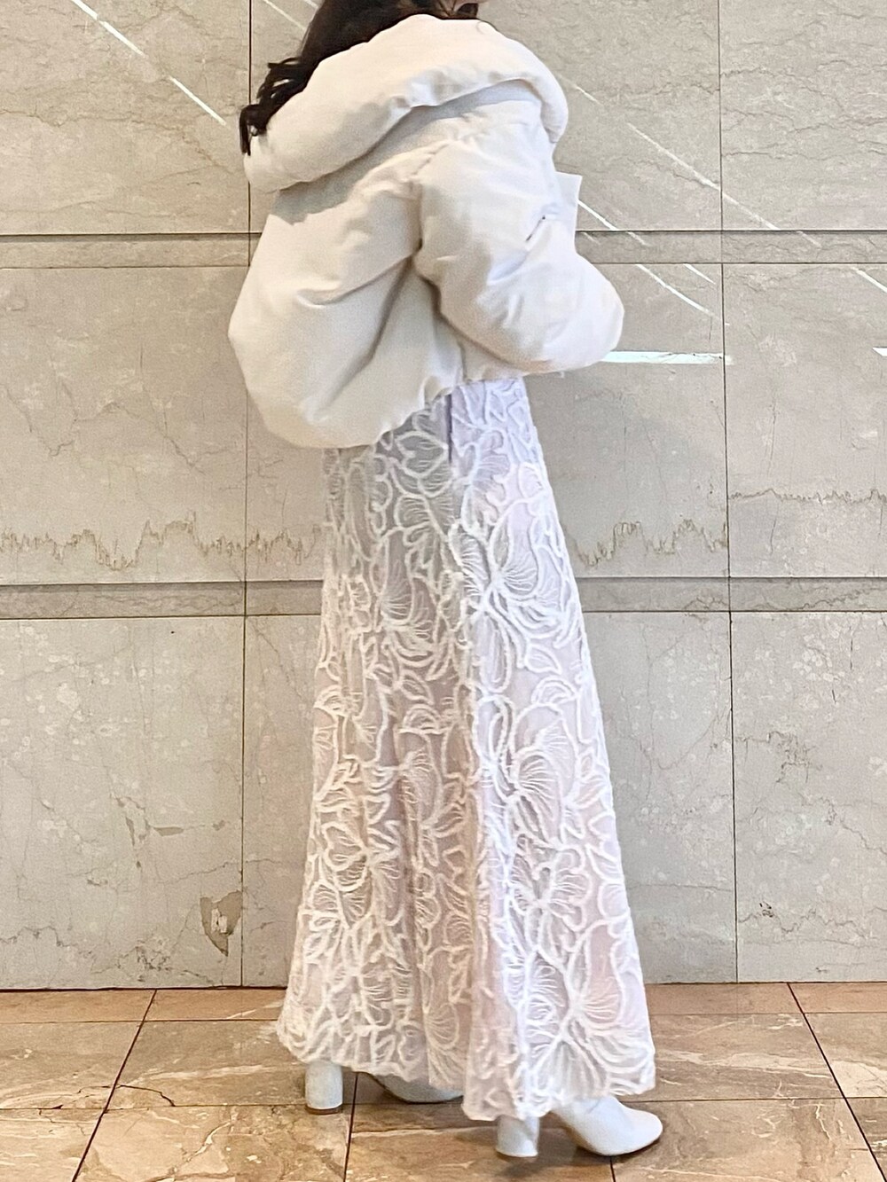 ピンク系のスカート、ホワイト系のニット/セーター、ホワイト系のダウンジャケット/コートを着用したレディースの冬コーディネートの3枚目の写真