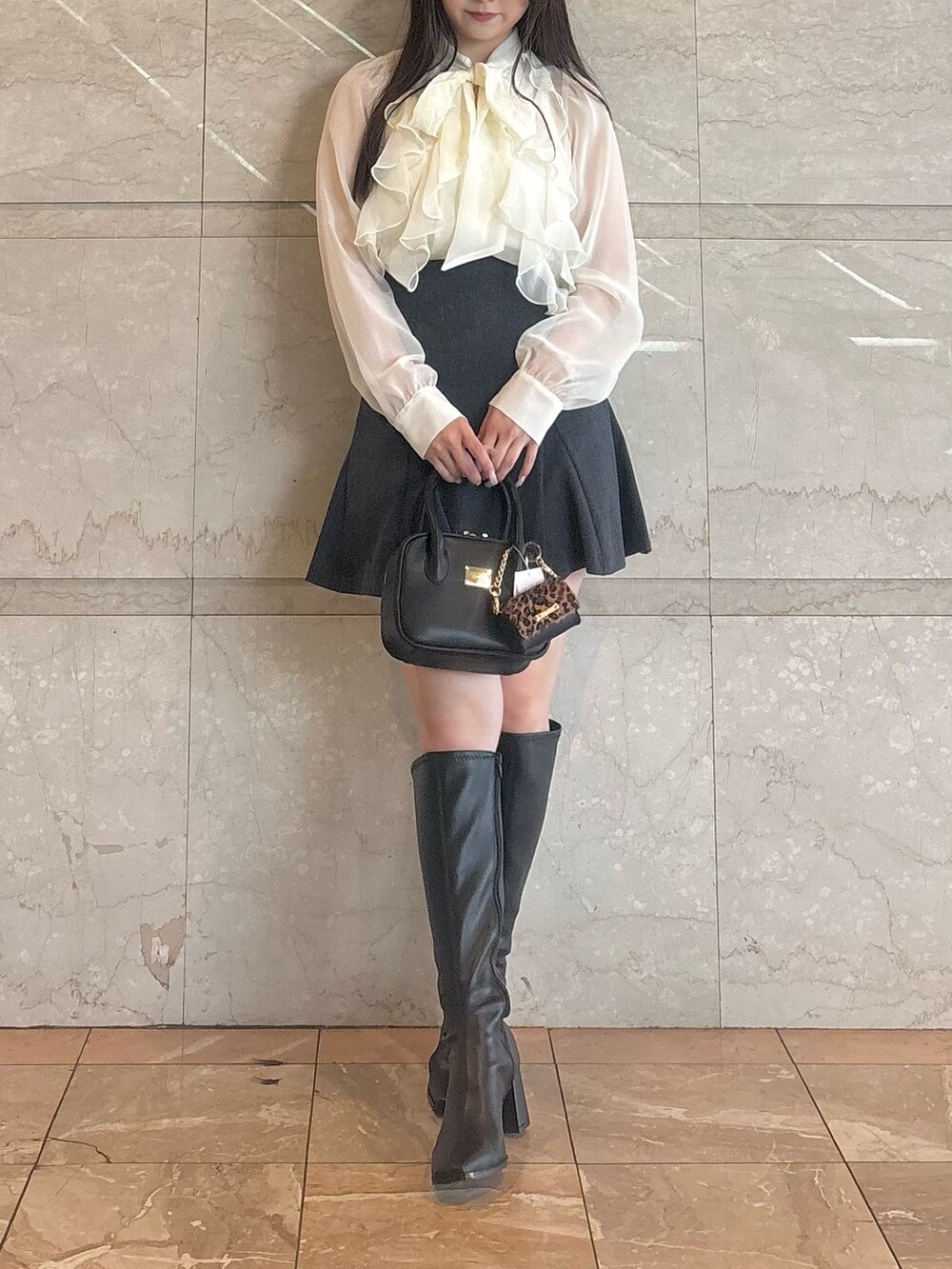 グレー系のスカート、ブラック系のブーツ、ブラック系のハンドバッグを着用したレディースの秋コーディネートの2枚目の写真