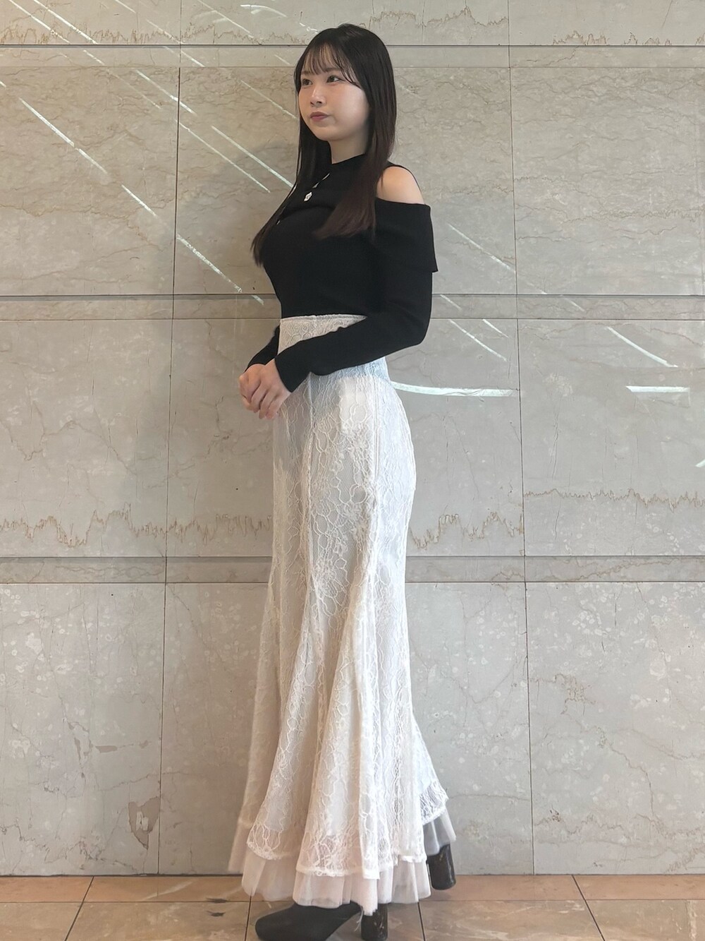 ホワイト系のスカート、ブラック系のブーツ、ブラック系のニット/セーターを着用したレディースの冬コーディネートの5枚目の写真