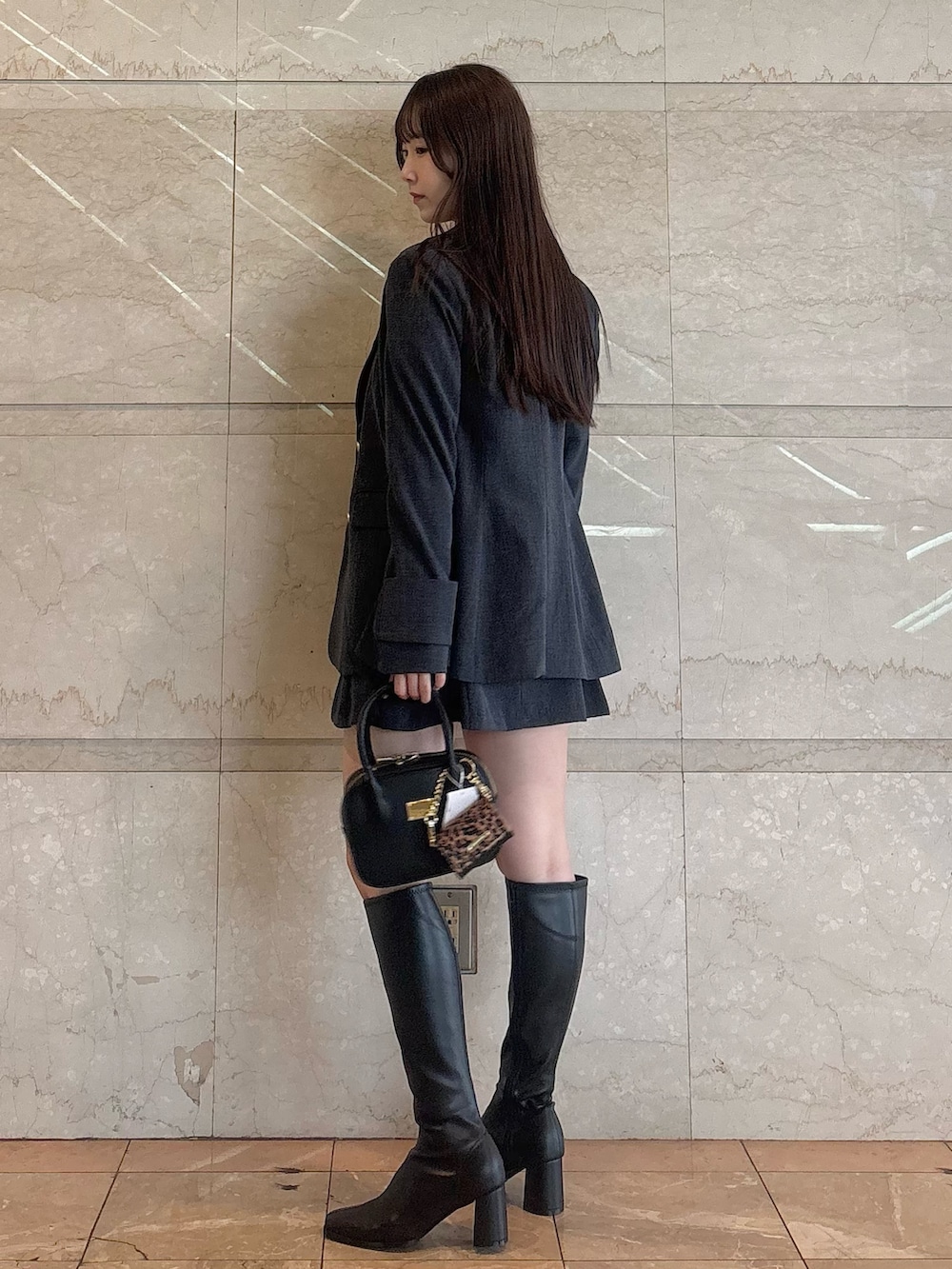 グレー系のスカート、ホワイト系のシャツ/ブラウス、ブラック系のハンドバッグを着用したレディースの秋コーディネートの3枚目の写真
