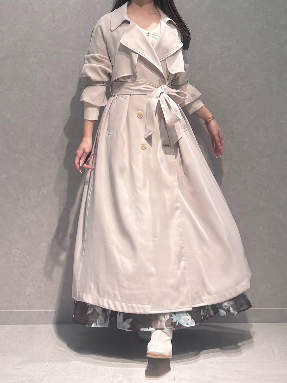 ブラウン系のスカート、ホワイト系のニット/セーター、ホワイト系のトレンチコートを着用したレディースの春コーディネートの2枚目の写真