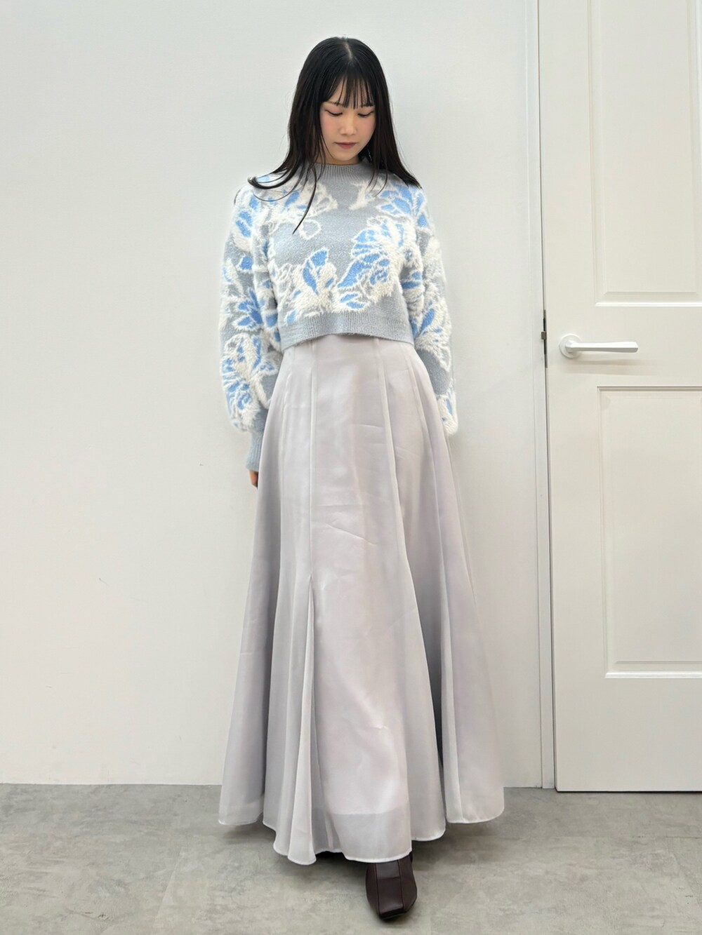 ブルー系のニット/セーター、ブラウン系のブーツ、グレー系のスカートを着用したレディースの秋コーディネートの2枚目の写真