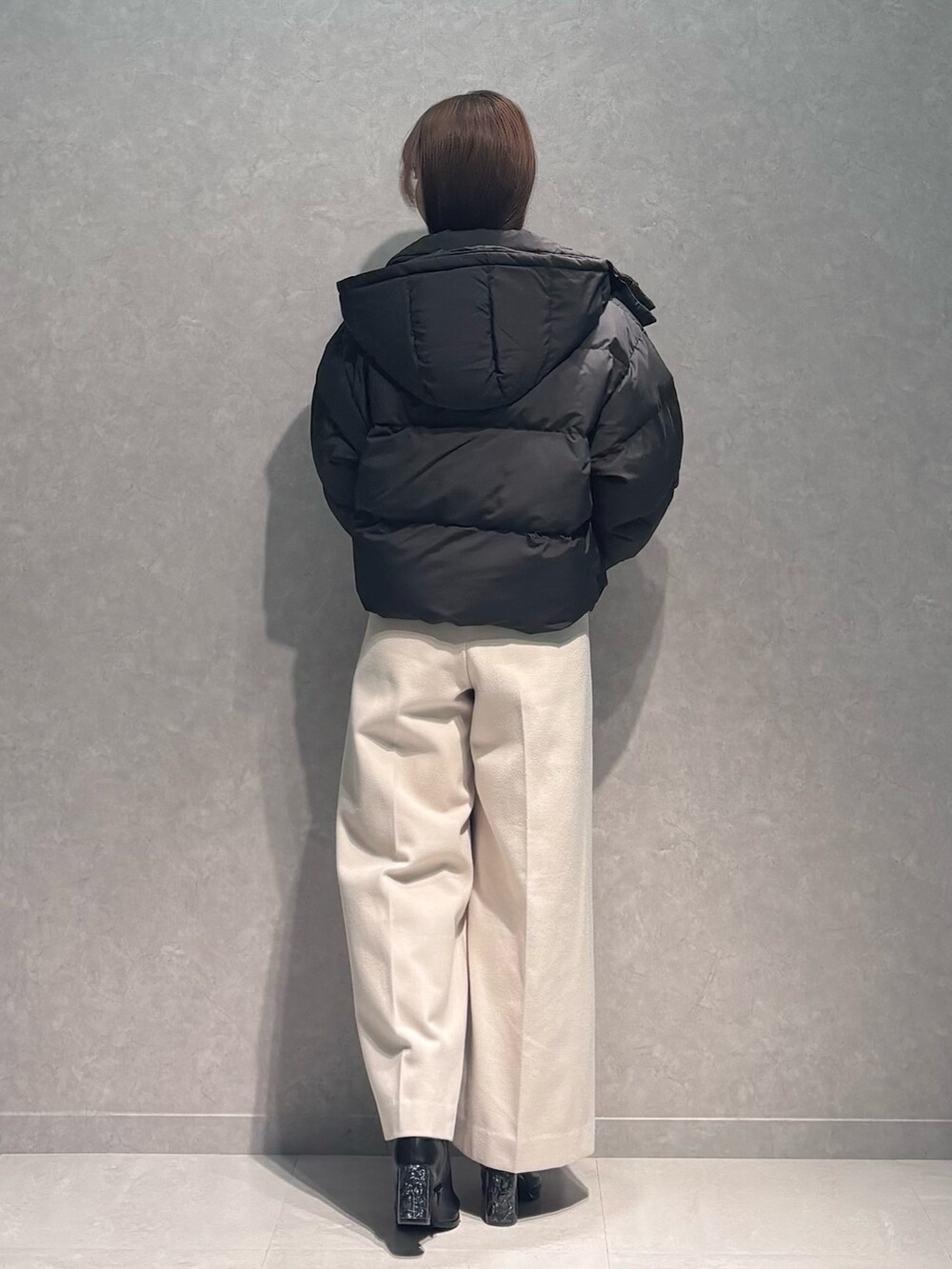 ホワイト系のワンピース、ブラック系のダウンジャケット/コート、ブラック系のブーツを着用したレディースの秋コーディネートの4枚目の写真