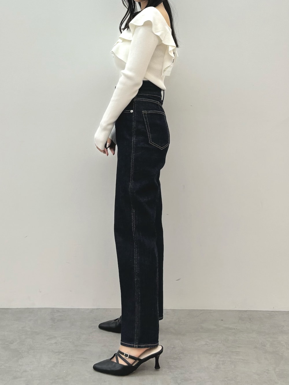 ブルー系のデニムパンツ、ブラック系のパンプス、ホワイト系のニット/セーターを着用したレディースの秋コーディネートの4枚目の写真