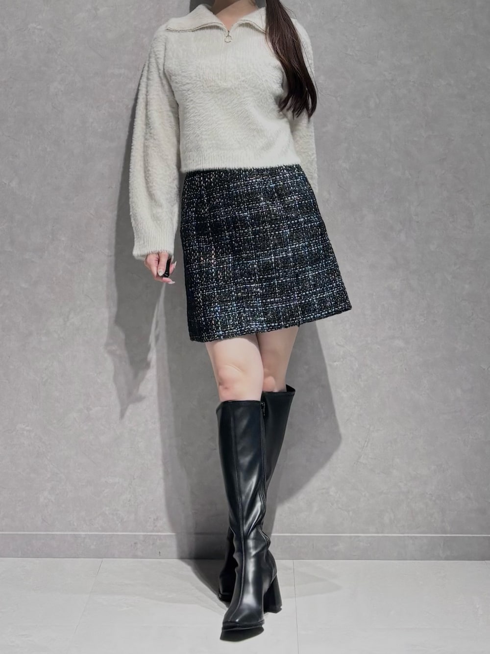 ブラック系のスカート、ブラック系のブーツ、ホワイト系のニット/セーターを着用したレディースの秋コーディネートの2枚目の写真