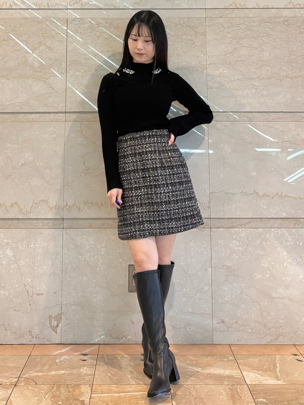 ブラック系のスカート、ブラック系のニット/セーター、ブラウン系のブーツを着用したレディースの冬コーディネートの2枚目の写真