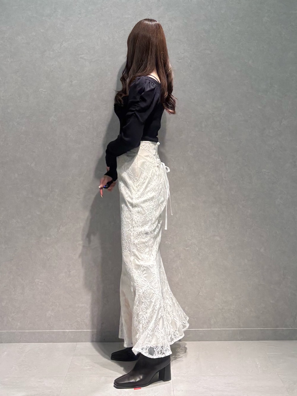 ホワイト系のスカート、ブルー系のニット/セーター、ブラウン系のブーツを着用したレディースの冬コーディネートの3枚目の写真