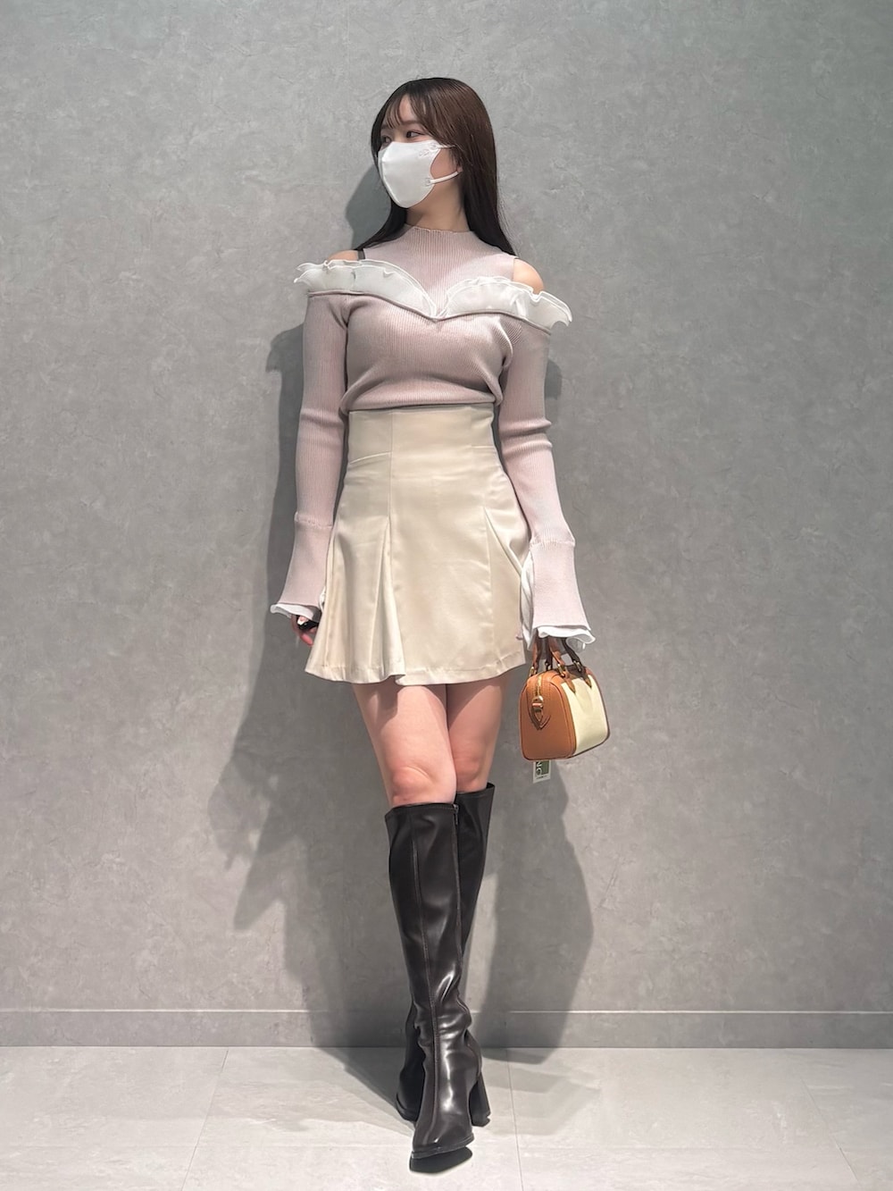 ベージュ系のニット/セーター、ホワイト系のスカート、ブラウン系のハンドバッグを着用したレディースの冬コーディネートの2枚目の写真