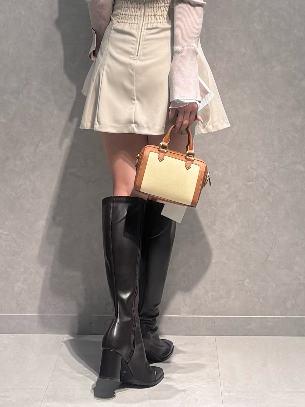 ベージュ系のニット/セーター、ホワイト系のスカート、ブラウン系のハンドバッグを着用したレディースの冬コーディネートの5枚目の写真