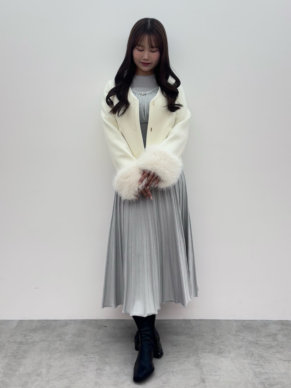 ブラック系のブーツ、ホワイト系のその他アウター、グレー系のワンピースを着用したレディースの冬コーディネートの2枚目の写真