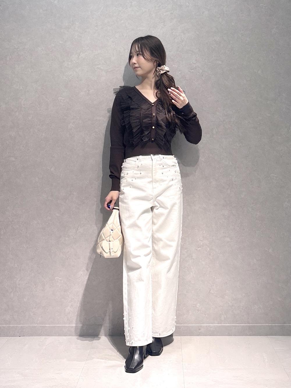 ホワイト系のデニムパンツ、ブラウン系のニット/セーター、ホワイト系のハンドバッグを着用したレディースの秋コーディネートの4枚目の写真