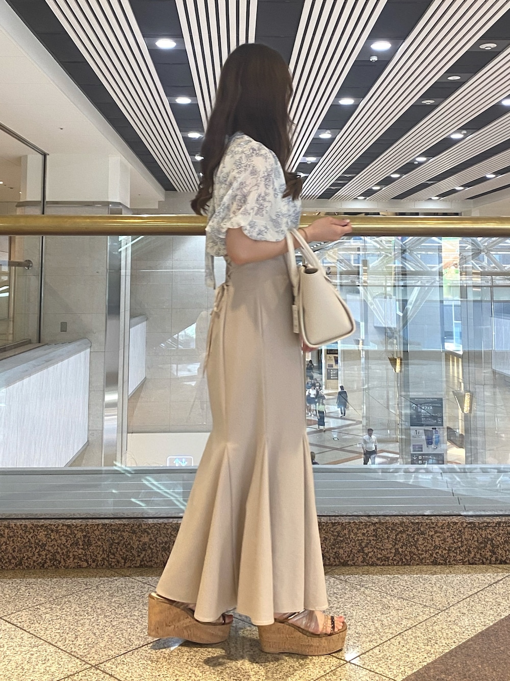 ベージュ系のスカート、ホワイト系のトートバッグ、ブルー系のシャツ/ブラウスを着用したレディースの夏コーディネートの3枚目の写真