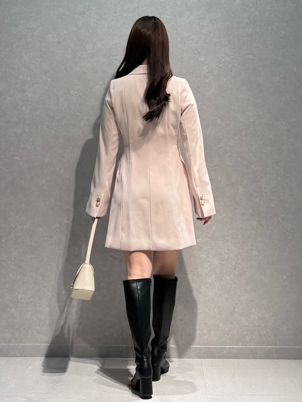 ピンク系のワンピース、ホワイト系のハンドバッグ、ブラック系のブーツを着用したレディースの春コーディネートの5枚目の写真