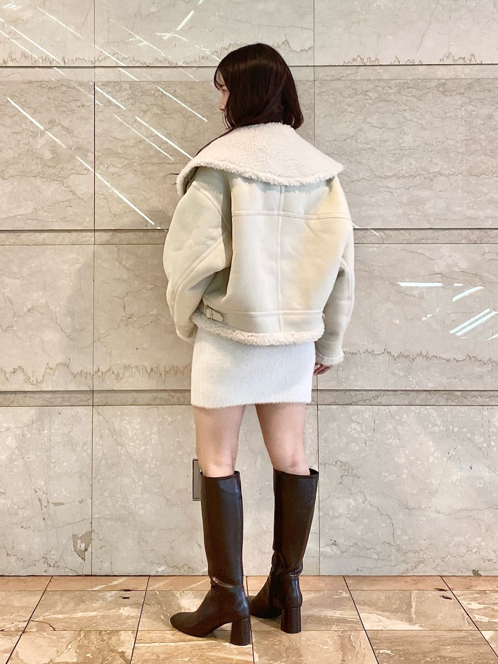ホワイト系のムートンコート、ホワイト系のワンピース、ブラウン系のブーツを着用したレディースの秋コーディネートの5枚目の写真
