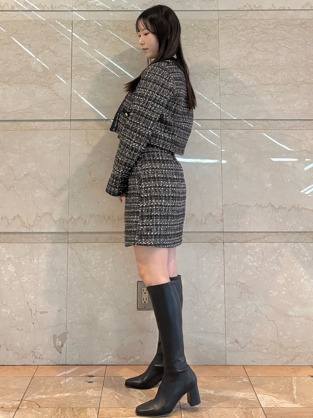 ブラック系のスカート、ブラック系のテーラードジャケット、ブラウン系のブーツを着用したレディースの冬コーディネートの3枚目の写真