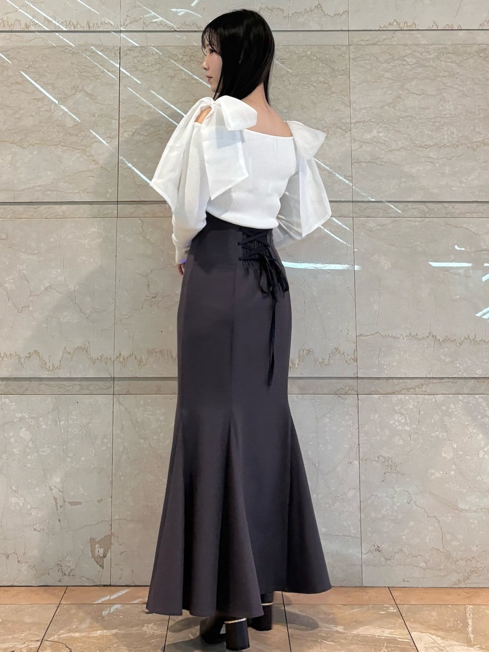 グレー系のスカート、ブラウン系のブーツ、ホワイト系のニット/セーターを着用したレディースの冬コーディネートの4枚目の写真