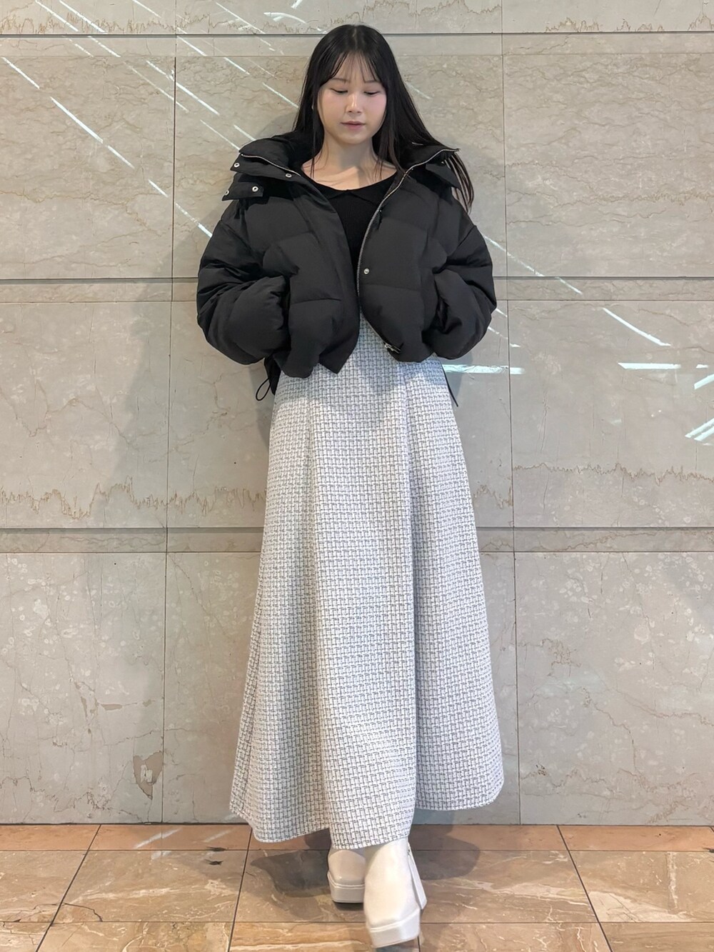 ホワイト系のスカート、ホワイト系のブーツ、ブラック系のダウンジャケット/コートを着用したレディースの冬コーディネートの3枚目の写真