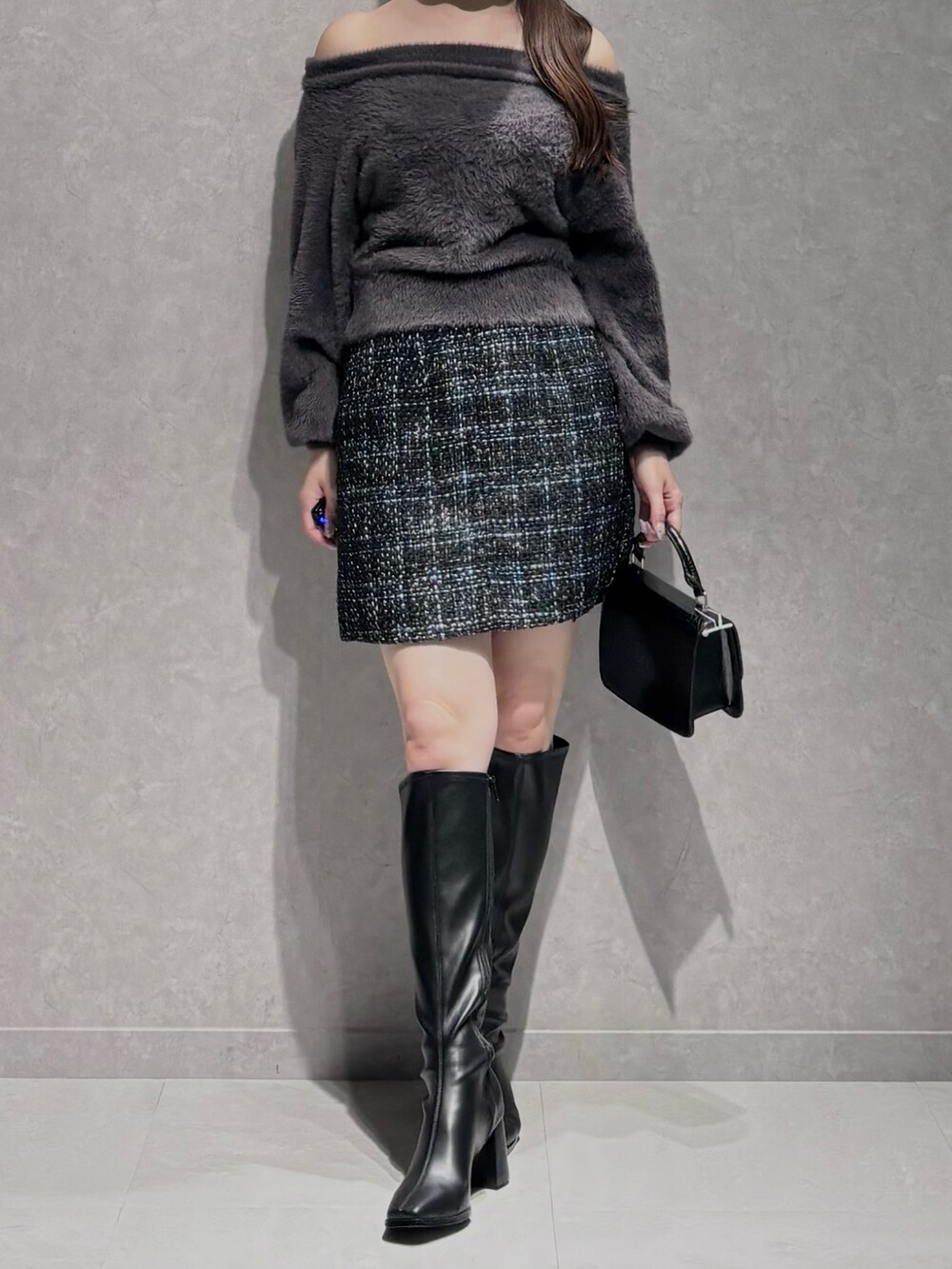 ブラック系のスカート、グレー系のニット/セーター、ブラック系のハンドバッグを着用したレディースの秋コーディネートの2枚目の写真
