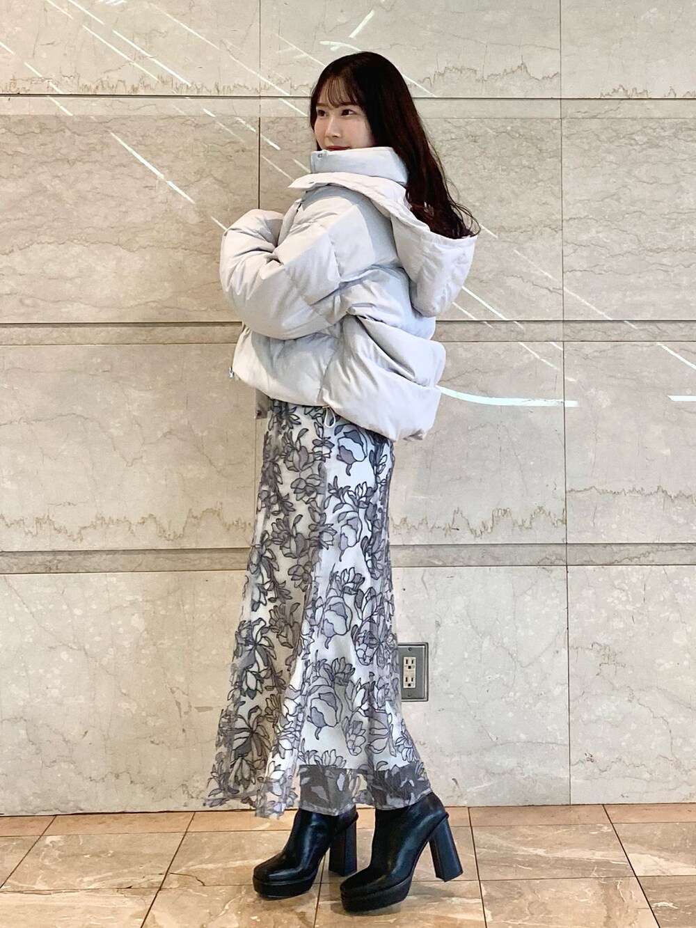 グレー系のスカート、グレー系のダウンジャケット/コート、グレー系のニット/セーターを着用したレディースの冬コーディネートの2枚目の写真