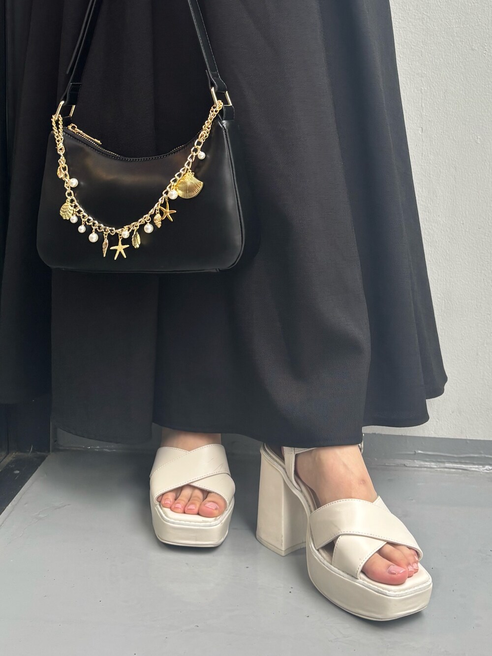 ブラック系のワンピース、ホワイト系のサンダル、ブラック系のハンドバッグを着用したレディースの夏コーディネートの7枚目の写真