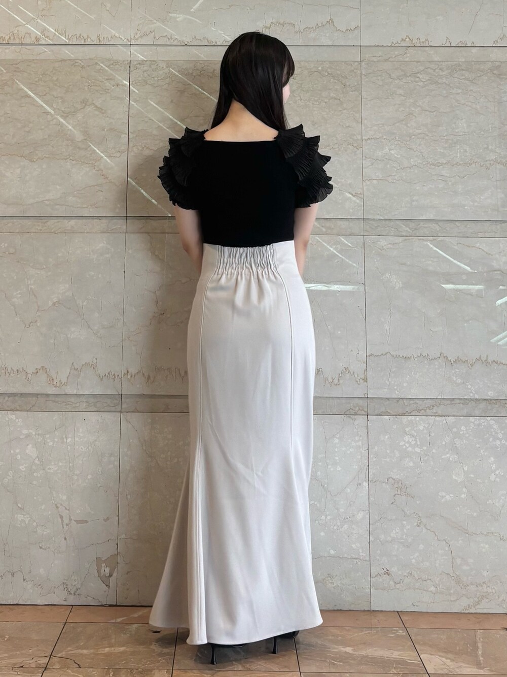 グレー系のスカート、ブラック系のニット/セーター、ブラック系のパンプスを着用したレディースの夏コーディネートの5枚目の写真