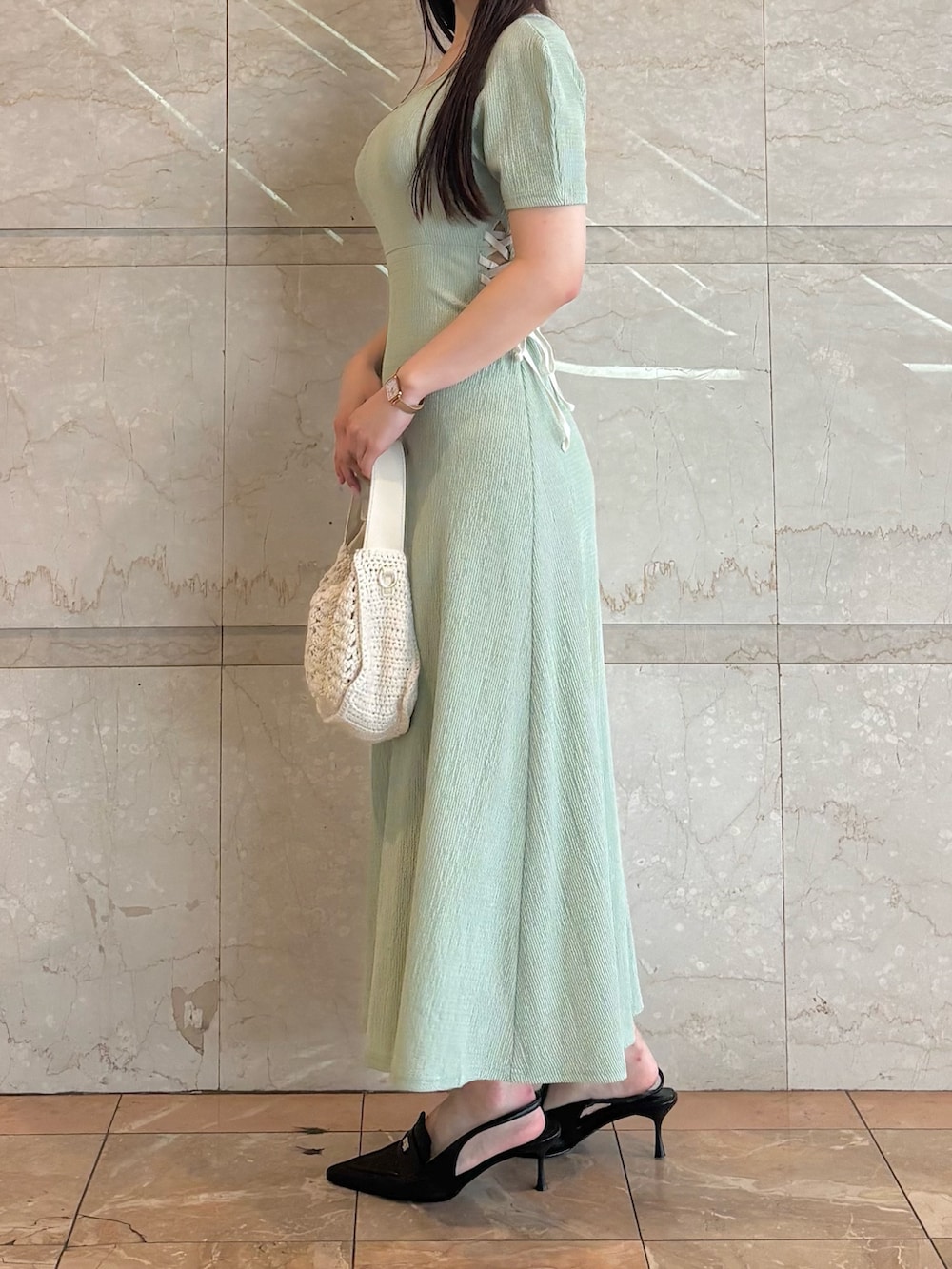 グリーン系のワンピース、ブラック系のパンプス、ホワイト系のショルダーバッグを着用したレディースの夏コーディネートの2枚目の写真