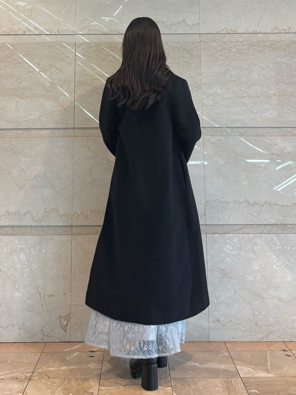 ブルー系のスカート、ブラック系のブーツ、ホワイト系のニット/セーターを着用したレディースの冬コーディネートの2枚目の写真