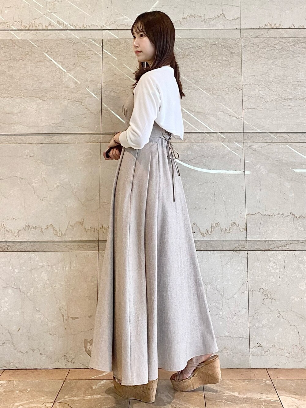 ベージュ系のワンピース、ホワイト系のカーディガン/ボレロ、その他のサンダルを着用したレディースの春コーディネートの4枚目の写真