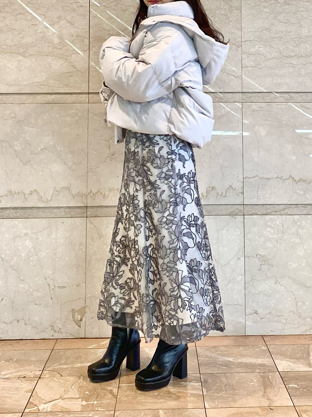 グレー系のスカート、グレー系のダウンジャケット/コート、グレー系のニット/セーターを着用したレディースの冬コーディネートの3枚目の写真