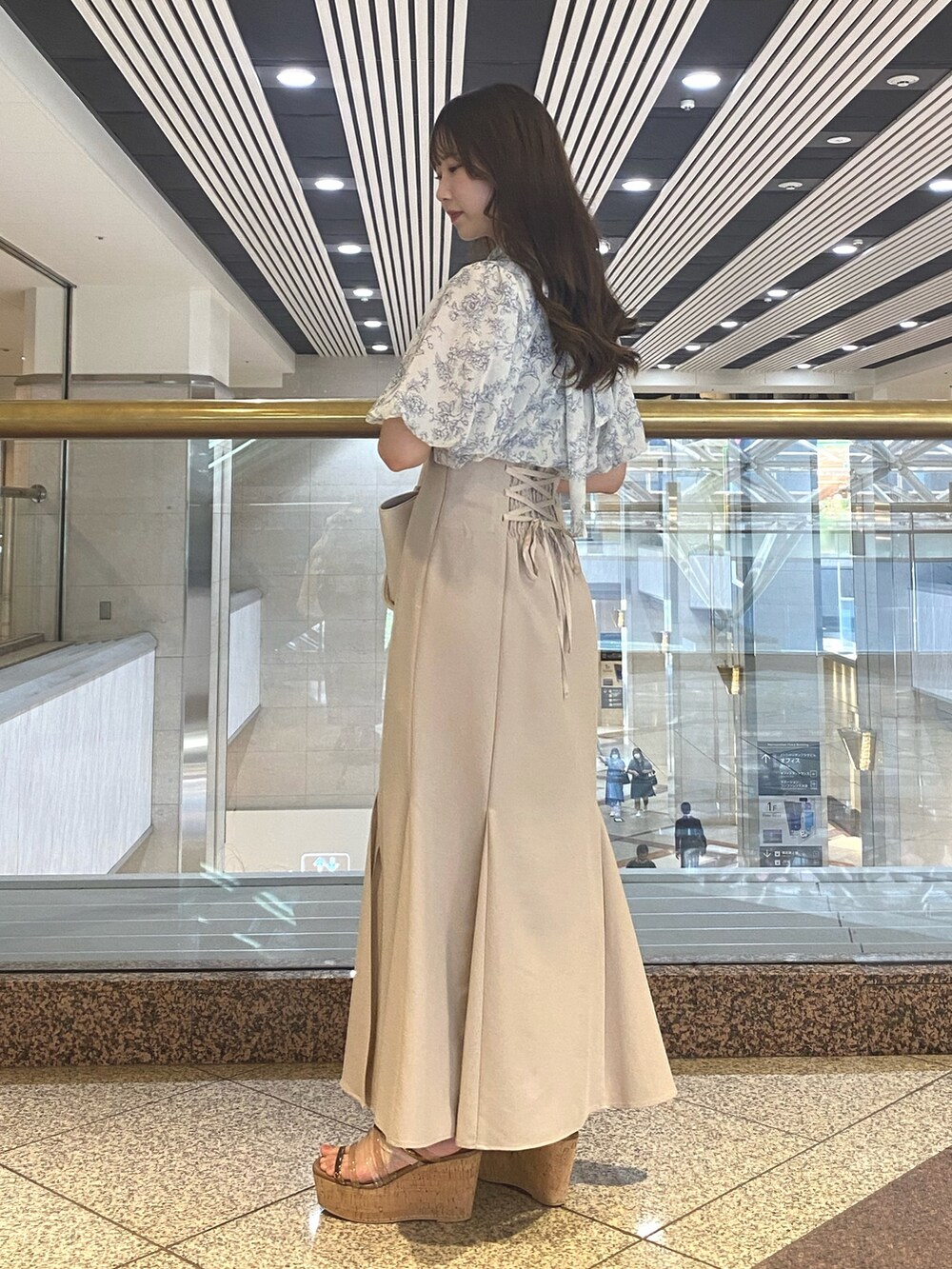 ベージュ系のスカート、ホワイト系のトートバッグ、ブルー系のシャツ/ブラウスを着用したレディースの夏コーディネートの2枚目の写真