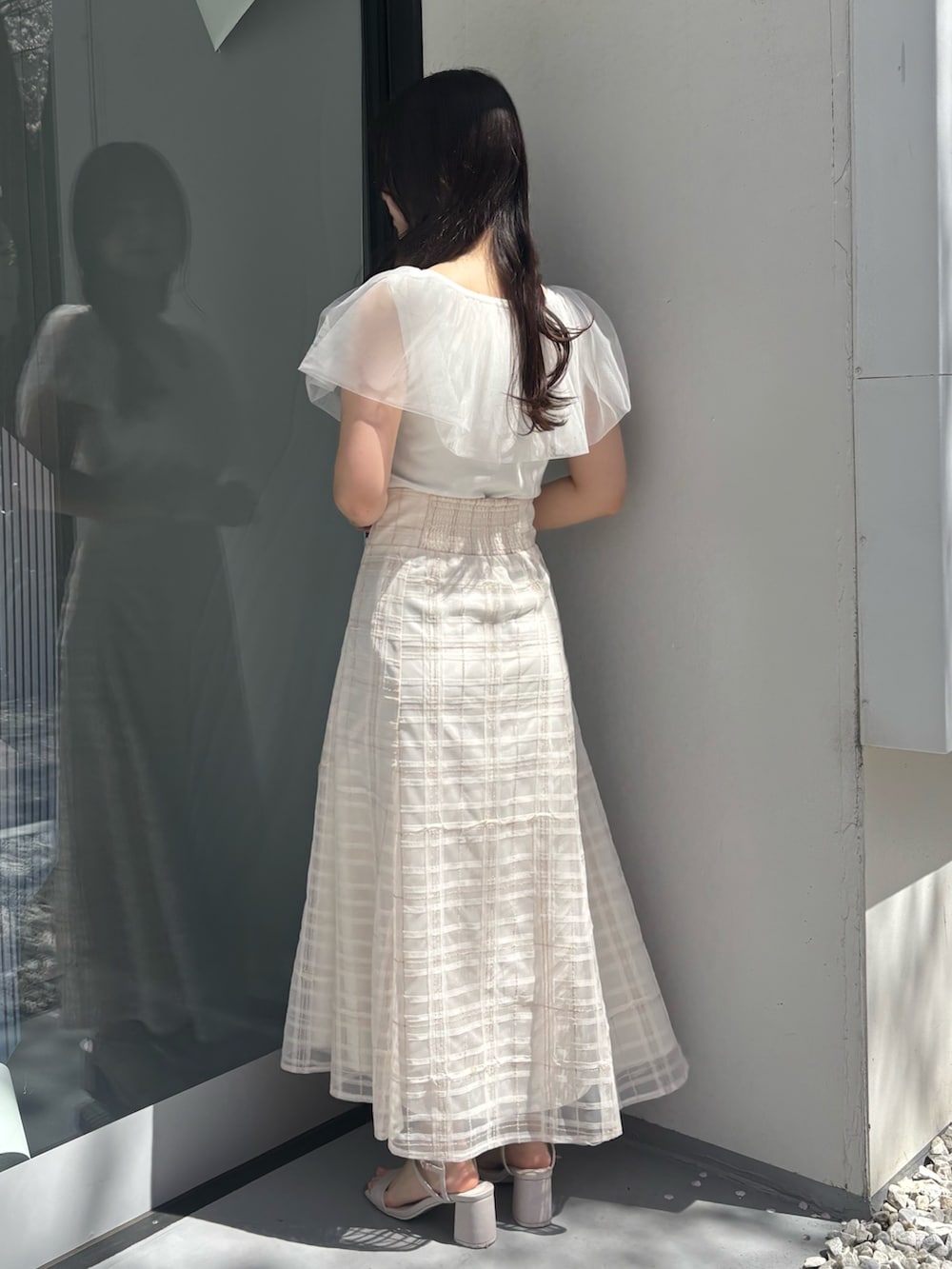 ホワイト系のスカート、ベージュ系のサンダル、ホワイト系のニット/セーターを着用したレディースの春コーディネートの3枚目の写真